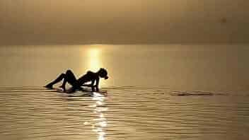 Monika Fox swims in sea at sunset